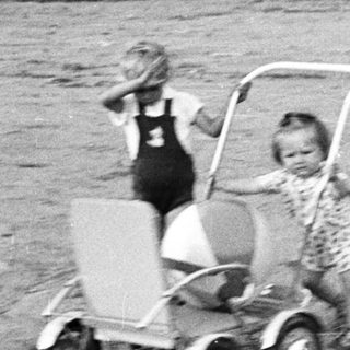 Two children playing with a wagon outdoors.