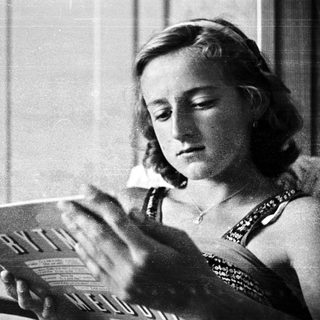 Woman reading sheet music in a vintage black and white photo.