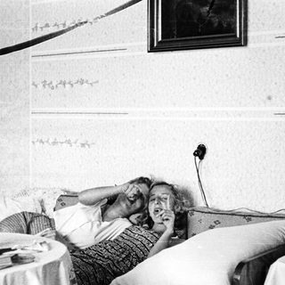 Here's a brief summary of the image: Woman lies in bed, appears to be listening intently.