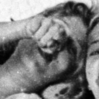 Here's a brief summary of the image: Woman lies in bed, appears to be listening intently.