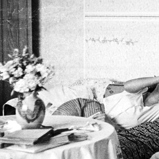 Here's a brief summary of the image: Woman lies in bed, appears to be listening intently.