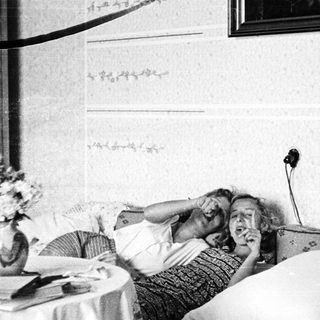 Here's a brief summary of the image: Woman lies in bed, appears to be listening intently.