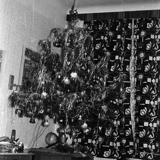 Black and white photo of a decorated Christmas tree indoors.