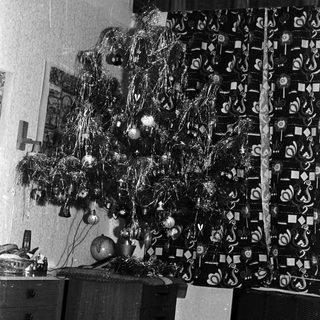 Black and white photo of a decorated Christmas tree indoors.