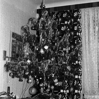 Black and white photo of a decorated Christmas tree indoors.