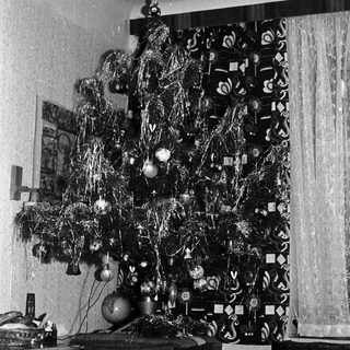 Black and white photo of a decorated Christmas tree indoors.