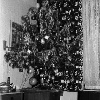 Black and white photo of a decorated Christmas tree indoors.