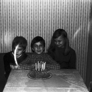 Three children blow out candles on a cake.