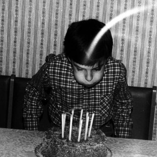 Child blowing out candles on a birthday cake.
