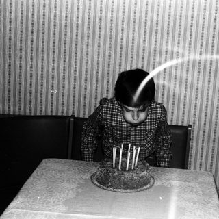 Child blowing out candles on a birthday cake.