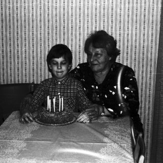 Boy with cake and older woman, possibly celebrating a birthday.