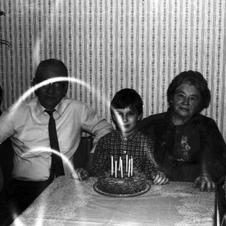 Family gathers around a cake, appearing to celebrate a birthday.