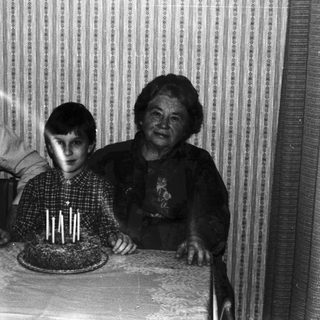 Family gathers around a cake, appearing to celebrate a birthday.