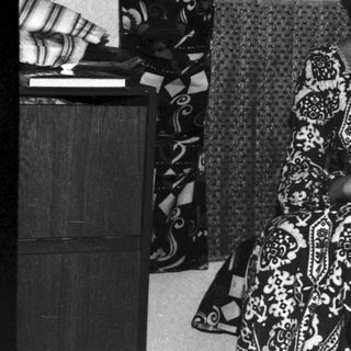 Woman and boy sit in a vintage, patterned room.