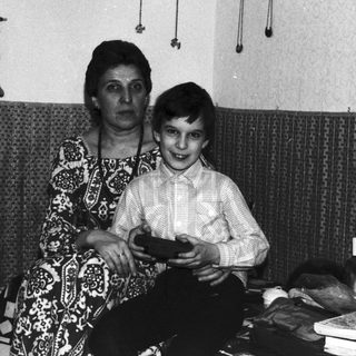 Woman and boy sit in a vintage, patterned room.