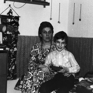 Woman and boy sit in a vintage, patterned room.