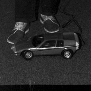 Boy operating a toy car in a room.