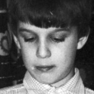 Boy operating a toy car in a room.