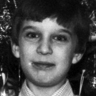 Boy holding a gift near a decorated wall.