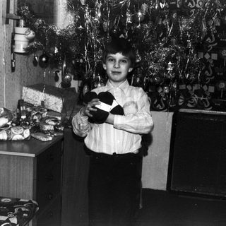 Boy holding a gift near a decorated wall.