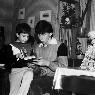 Two boys reading a book together at a table.
