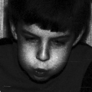 Black and white photo of a boy blowing out candles.