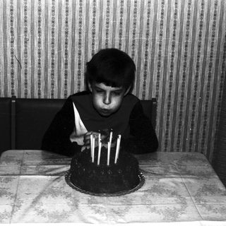 Black and white photo of a boy blowing out candles.