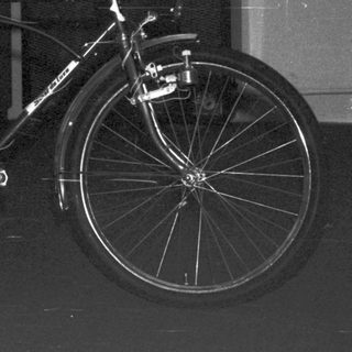 Boy in pajamas poses with a vintage bicycle indoors.
