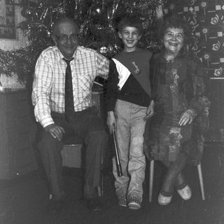 Black and white photo of three people near a Christmas tree.