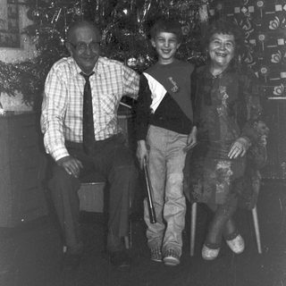 Black and white photo of three people near a Christmas tree.