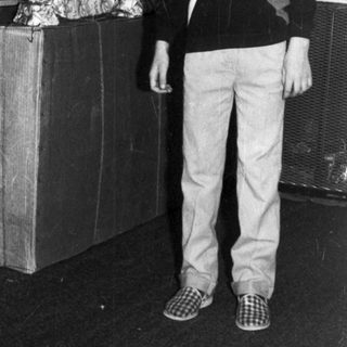 Boy stands near a Christmas tree and wrapped gifts.