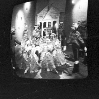 Group of people in costumes standing near a building.