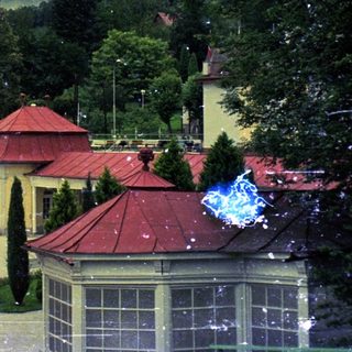 Here's a brief summary of the image: Building complex with red roofs and lush greenery.