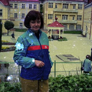 Woman stands in flooded miniature town, observing the scene.