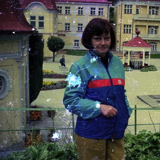 Woman stands in flooded miniature town, observing the scene.