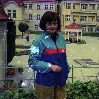 Woman stands in flooded miniature town, observing the scene.