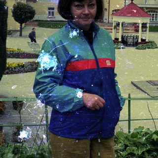 Woman stands in flooded miniature town, observing the scene.