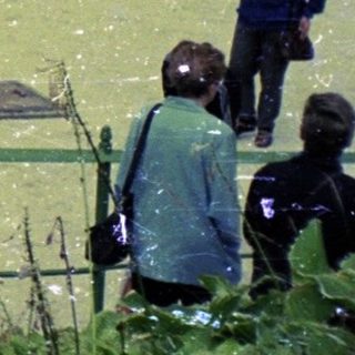 Woman stands in flooded miniature town, observing the scene.