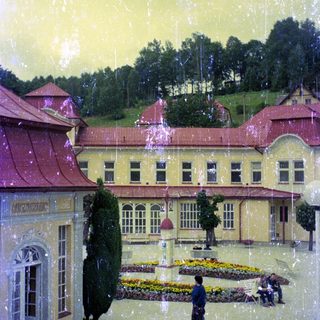 Building with garden, people, and trees in a scenic area.