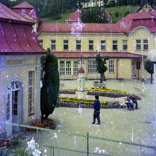 Building with garden, people, and trees in a scenic area.