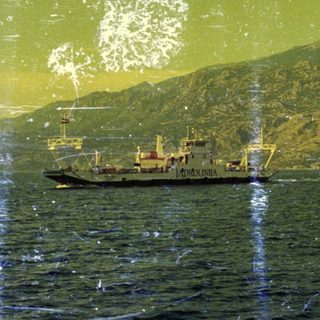 A ship sails past a coastline with mountains.
