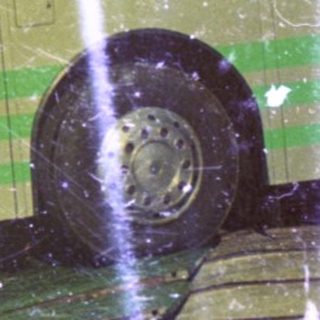 A green bus is parked, with an airplane wing visible.