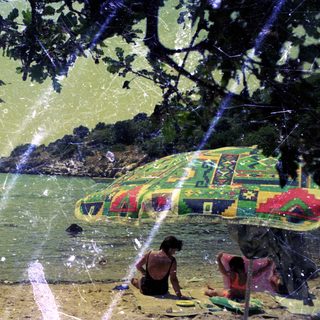 People relax on a beach under a patterned umbrella.