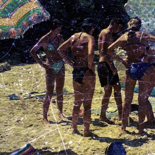 Group of people on a sunny beach with swimwear.