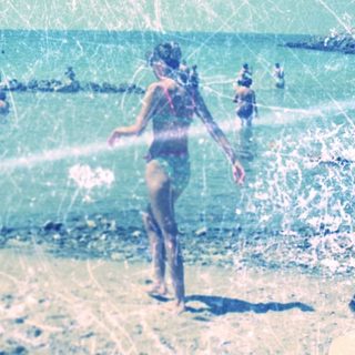 A person on a beach with waves and blue sky.