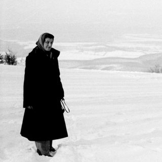Woman stands in a snowy, barren landscape.