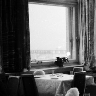 Man seated in a formally set, dimly lit restaurant.