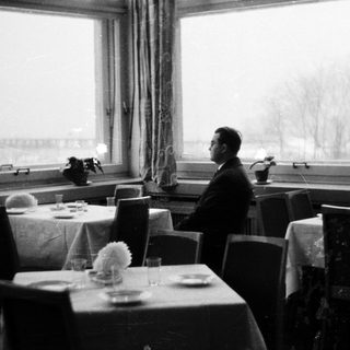Man seated in a formally set, dimly lit restaurant.