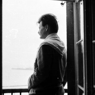 Man stands in doorway, looking out toward a view.