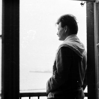 Man stands in doorway, looking out toward a view.